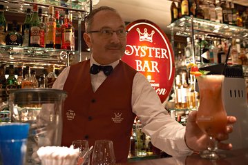 [Translate to English:] Barkeeper mixt Cocktail in der Oysterbar des Fischereihafen Restaurants